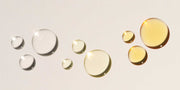 image of liquid drops on beige background ranging in color from clear to a light yellow
